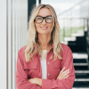 Personne souriante portant des lunettes et croisant les bras