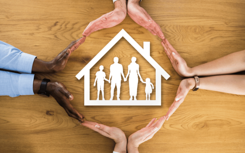 Mains entourant une maison, représentant le concept d’assurance de personne pour une famille
